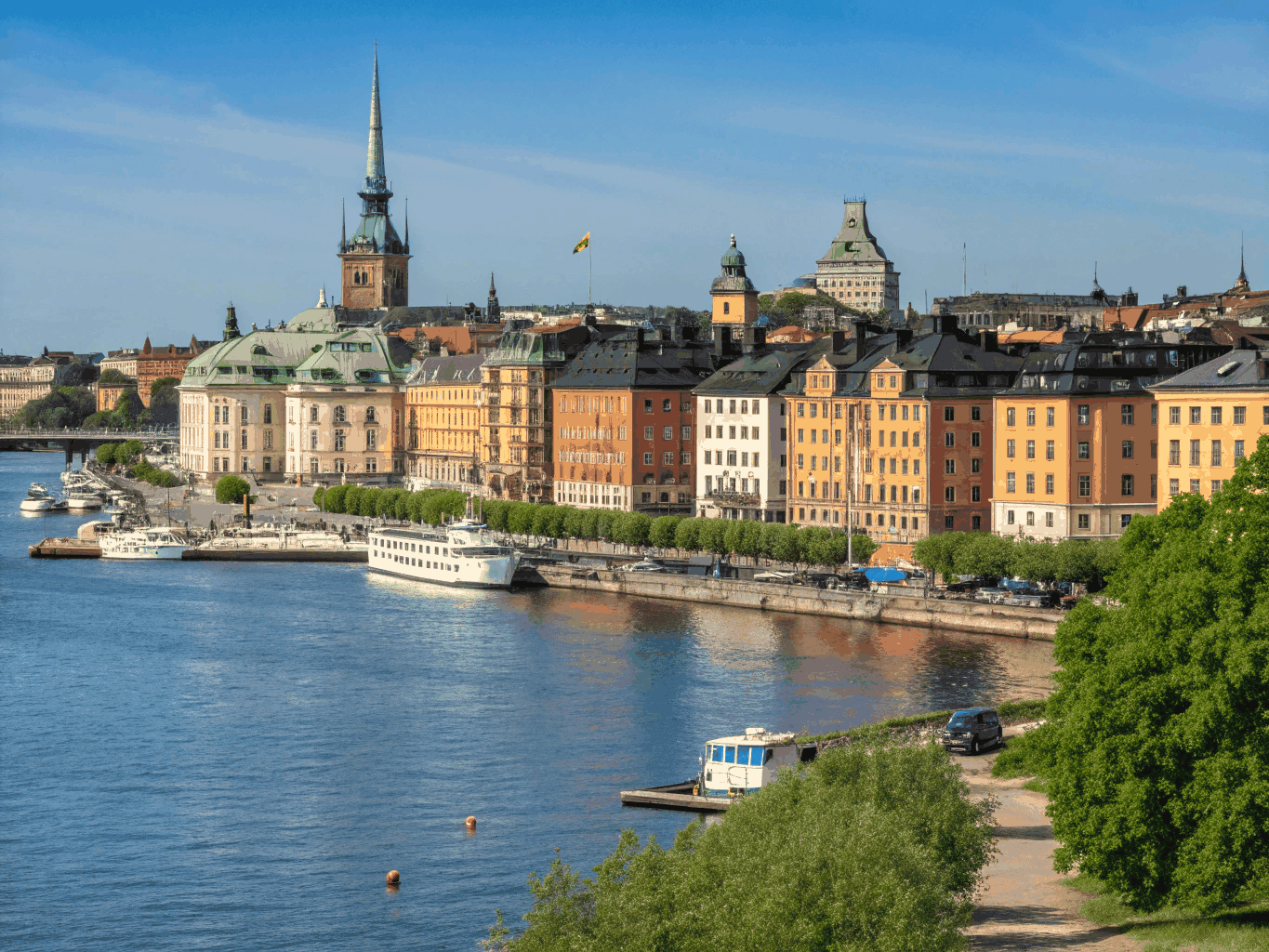 Vibrant Stockholm archipelago island community with red wooden summer houses, active sailing boats, and waterfront boardwalks