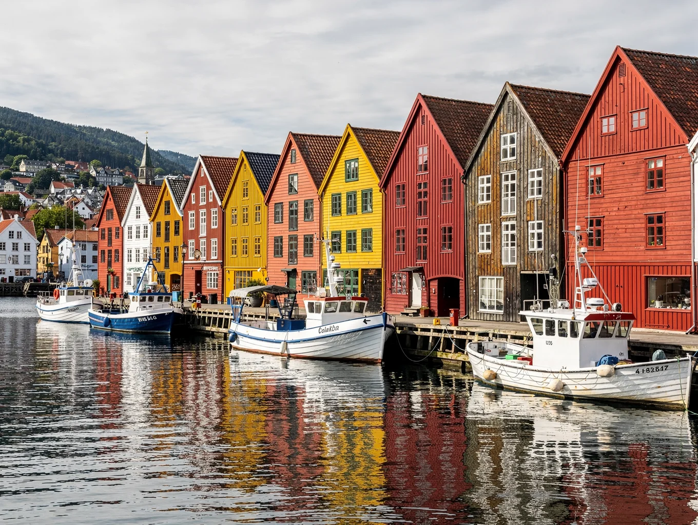 Historic colorful wooden wharf houses along Bergen harbor under misty hills