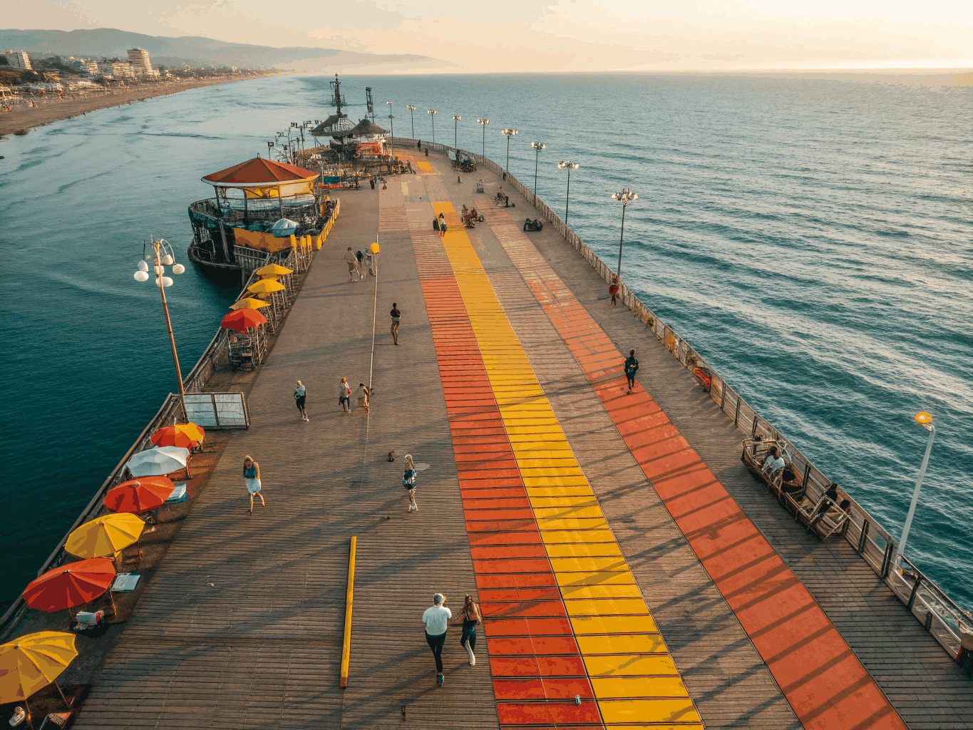 Long historic wooden pier stretching into rolling Pacific surf at sunset in Huntington Beach