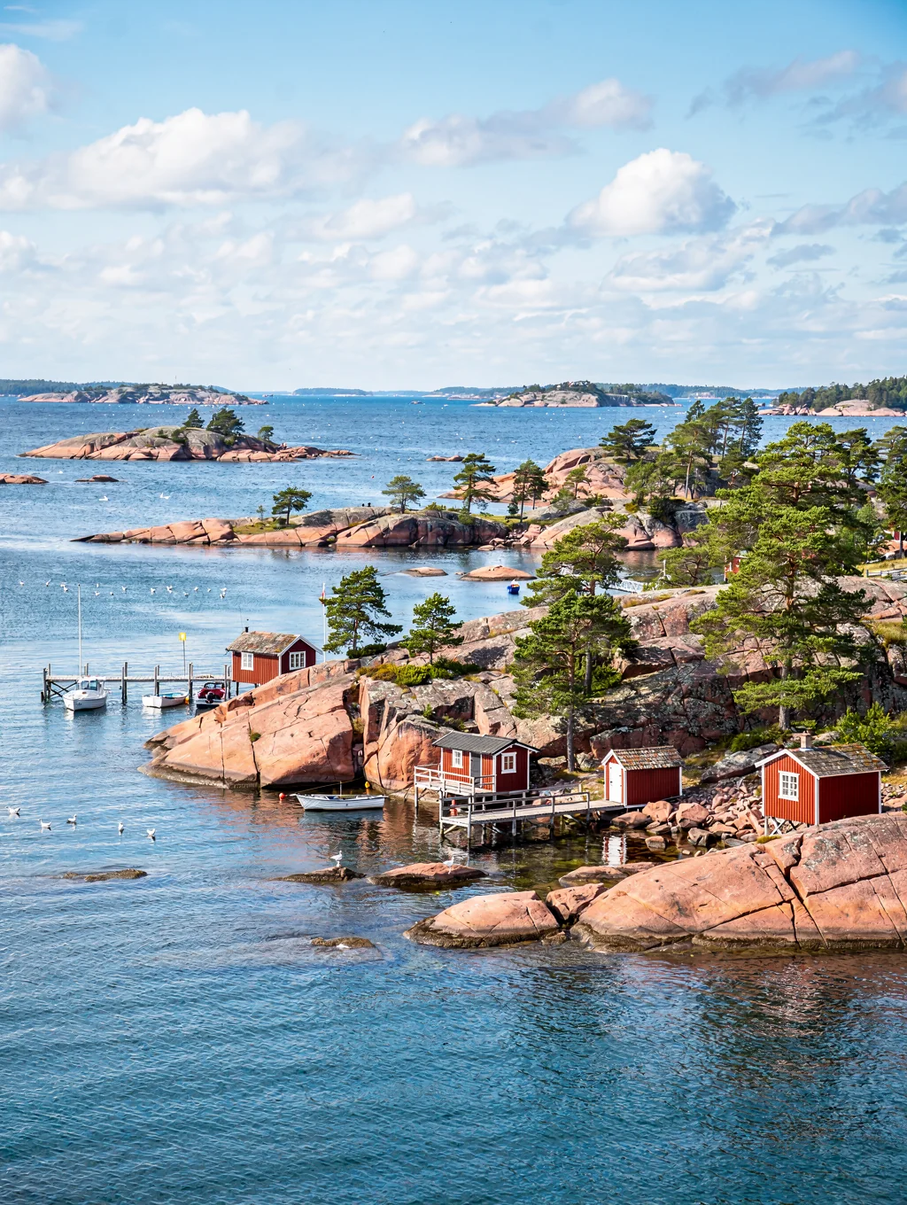 Red granite rocky shores and evergreen pine trees overlooking tranquil coastal waters in the Åland Islands