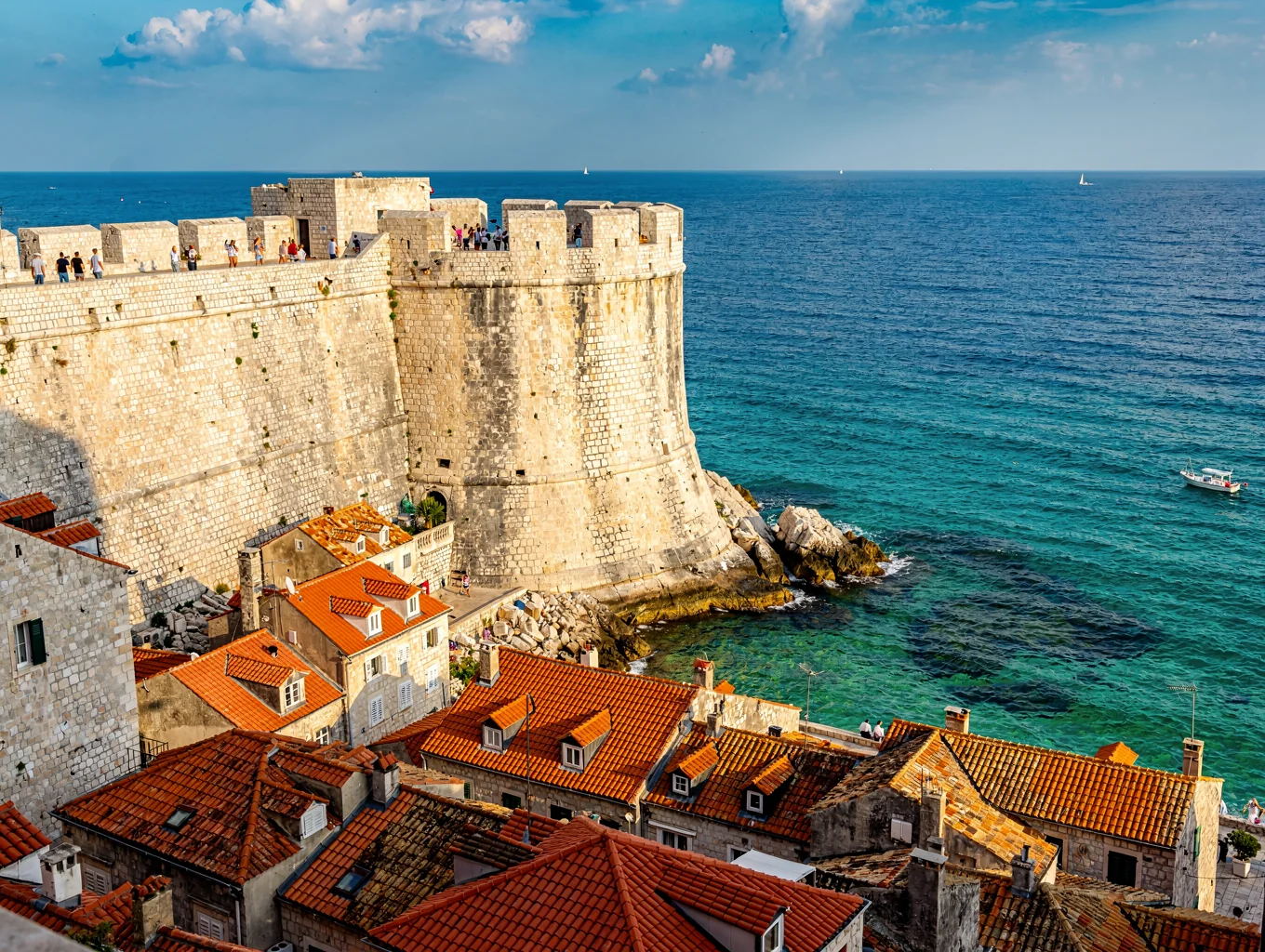 Gamle festningsmurer i stein som møter det turkise havet i Dubrovnik