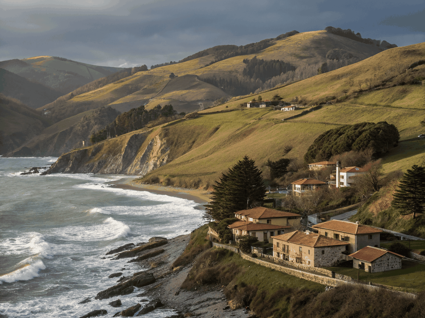 Traditional Basque farmhouse overlooking green coastal hills and ocean estuary
