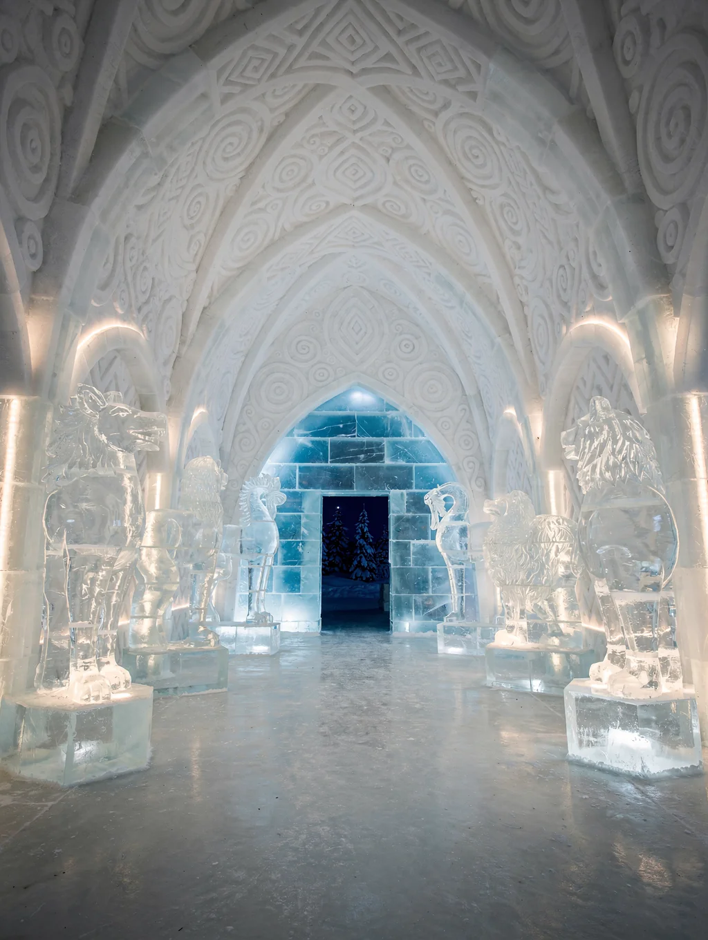 Intricately sculpted ice arches and crystalline frozen art installations illuminated inside an ice hotel near Kiruna