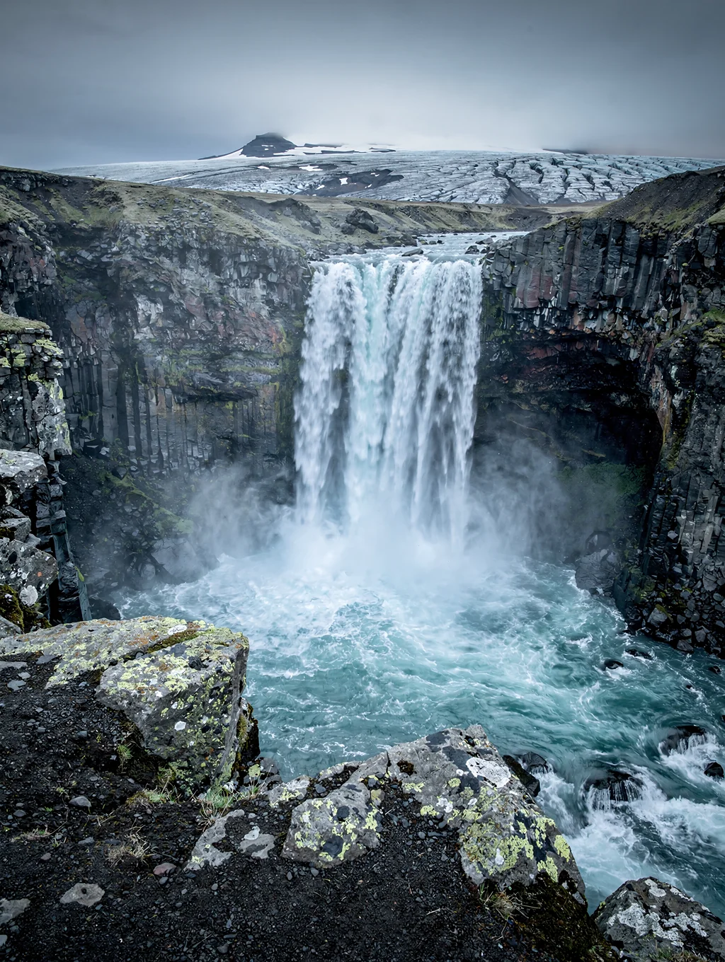 Cascading glacial waterfalls pouring down sheer rocky canyon cliffs directly into Geirangerfjord