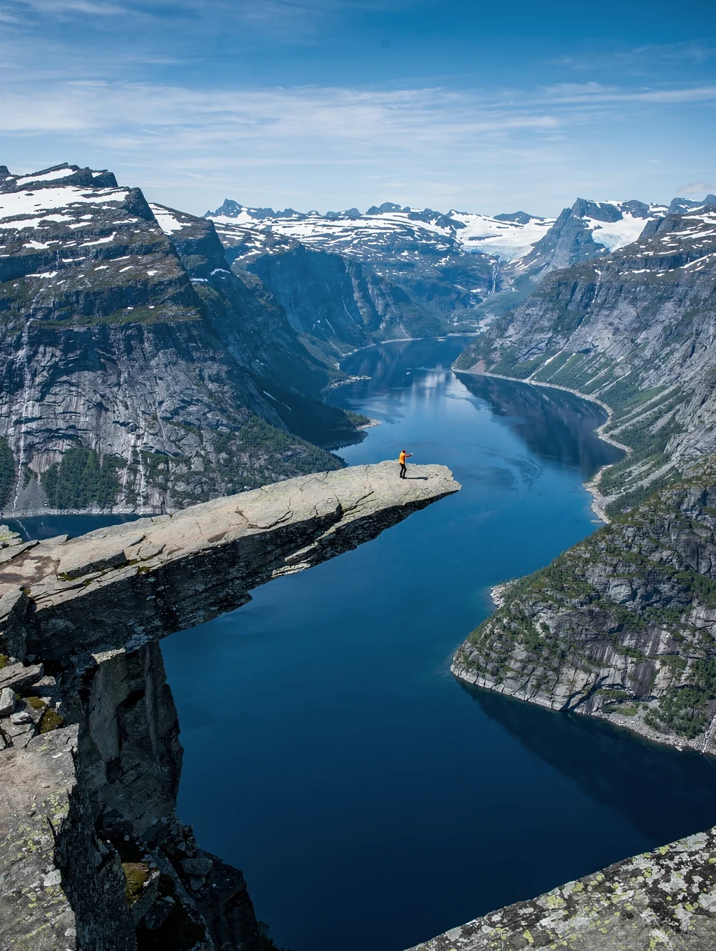 Iconic horizontal rock plateau of Trolltunga projecting high above an azure mountain reservoir in Norway