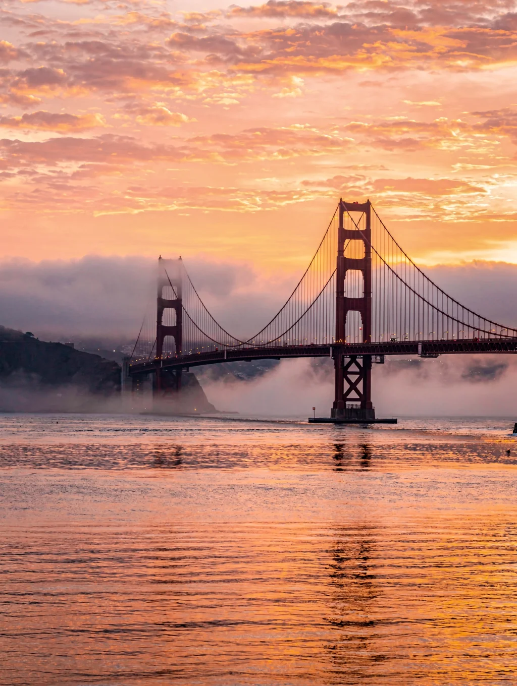 Golden Gate Bridge illuminated against a warm evening sunset sky