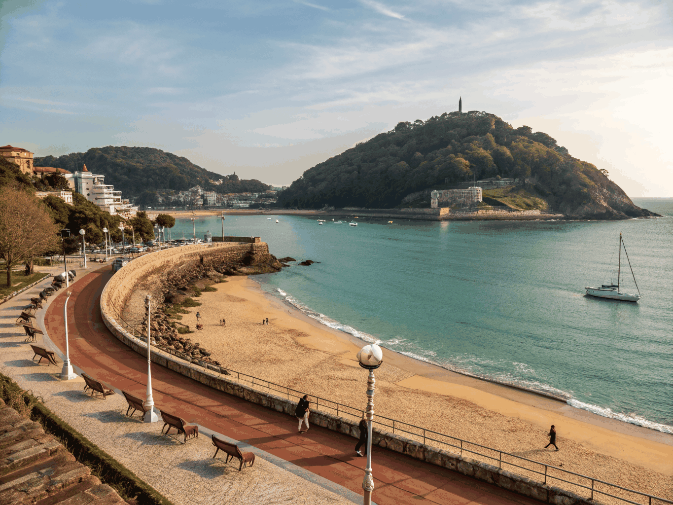 Curving promenade of La Concha bay with gentle turquoise waves and white railings