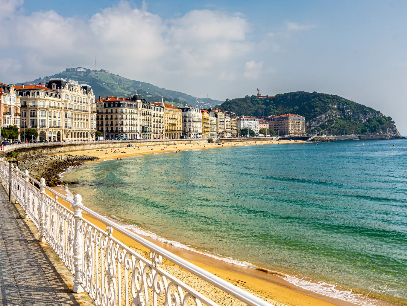 Curving promenade of La Concha bay with gentle turquoise waves and white railings