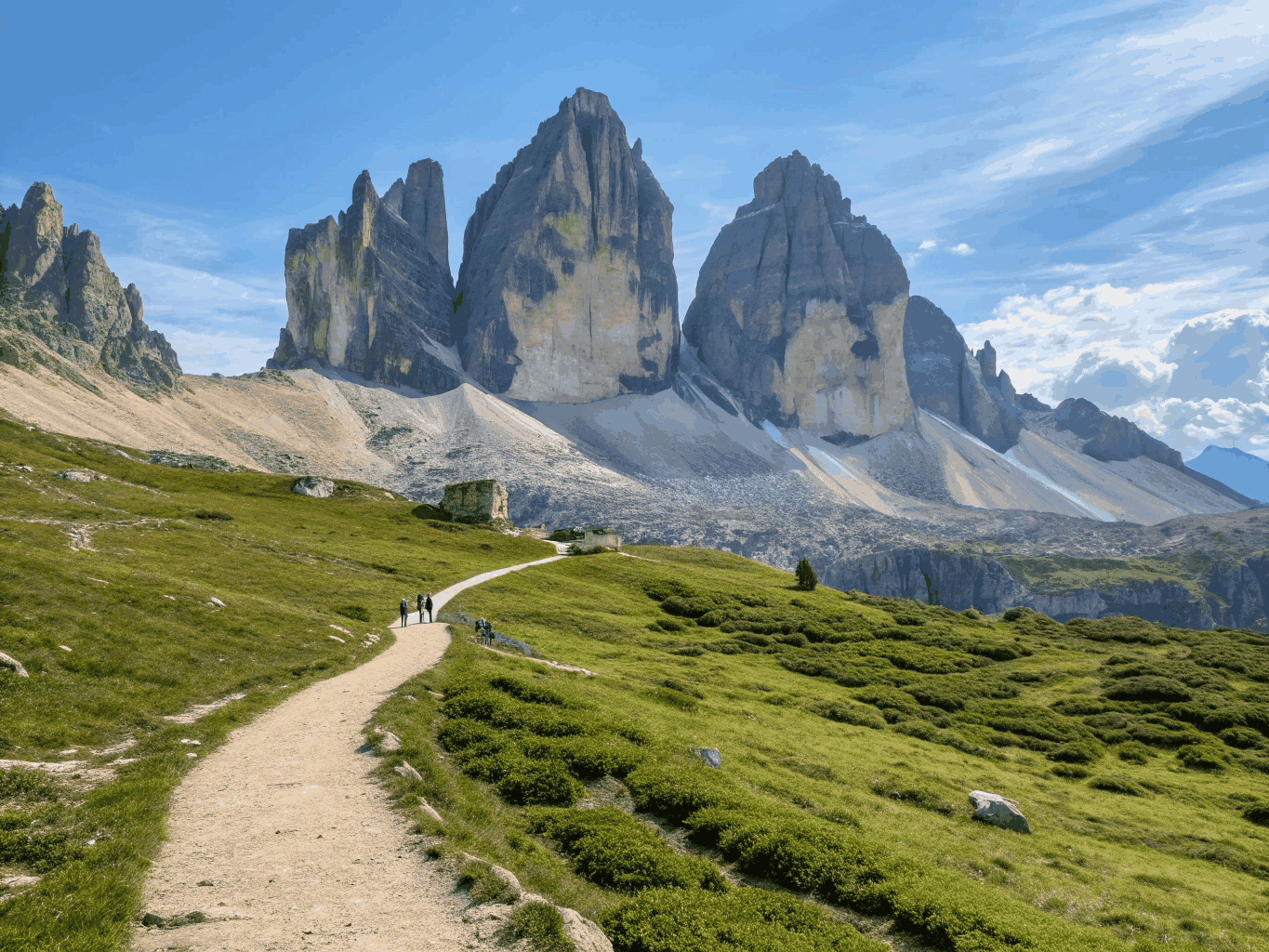 Three dramatic limestone mountain towers bathed in warm alpine sunset light