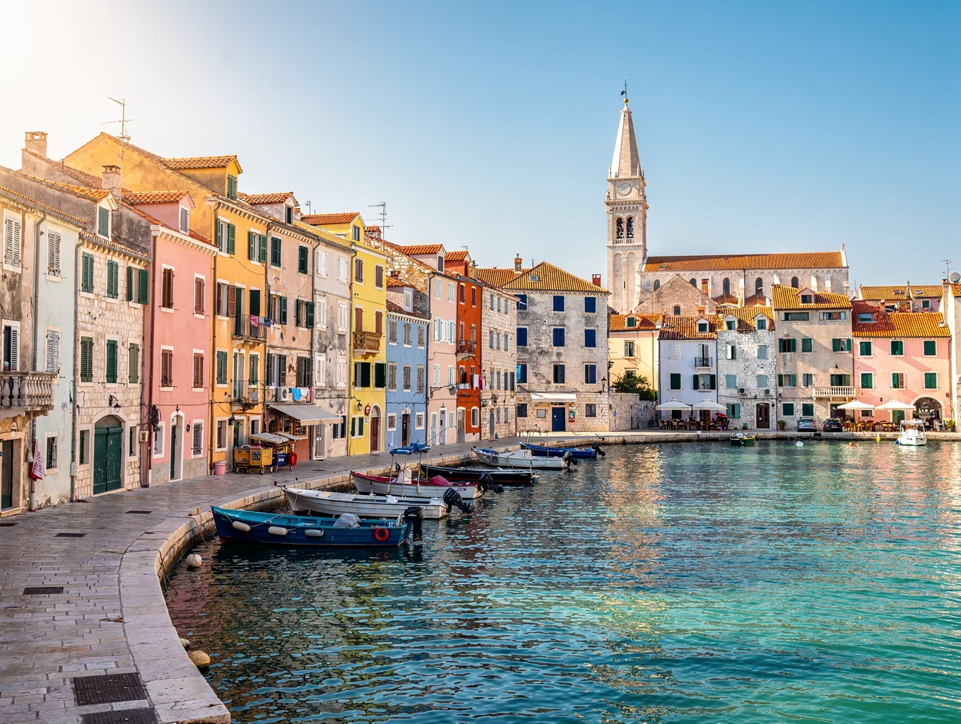 Pastel seaside village houses crowded along a curving rocky harbor