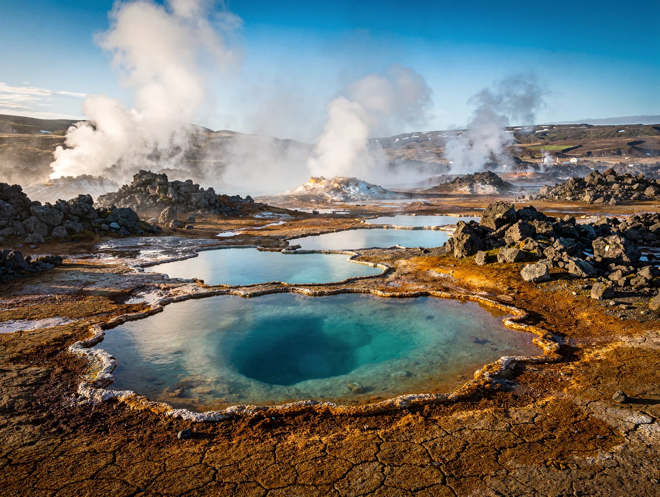 Steaming geothermal vents across vivid green Icelandic moss-covered hills