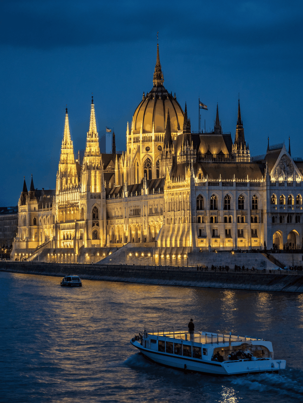 Illuminated Hungarian Parliament and historic stone bridges reflected in the Danube River at dusk