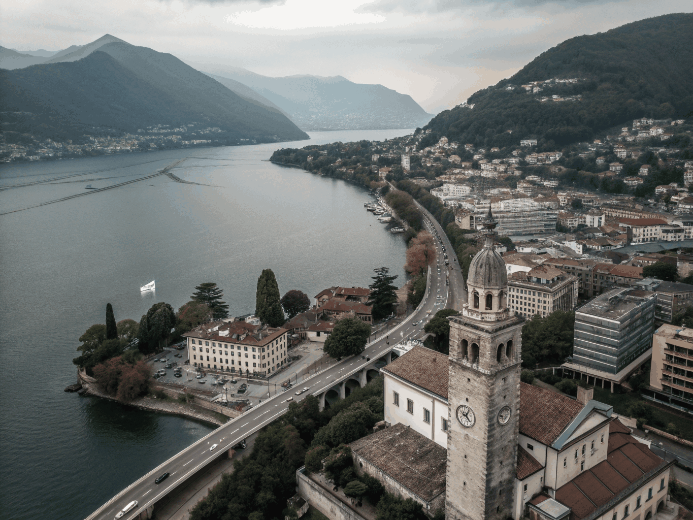 Aerial view over the historic lakeside town of Lugano with church tower and surrounding alpine mountains