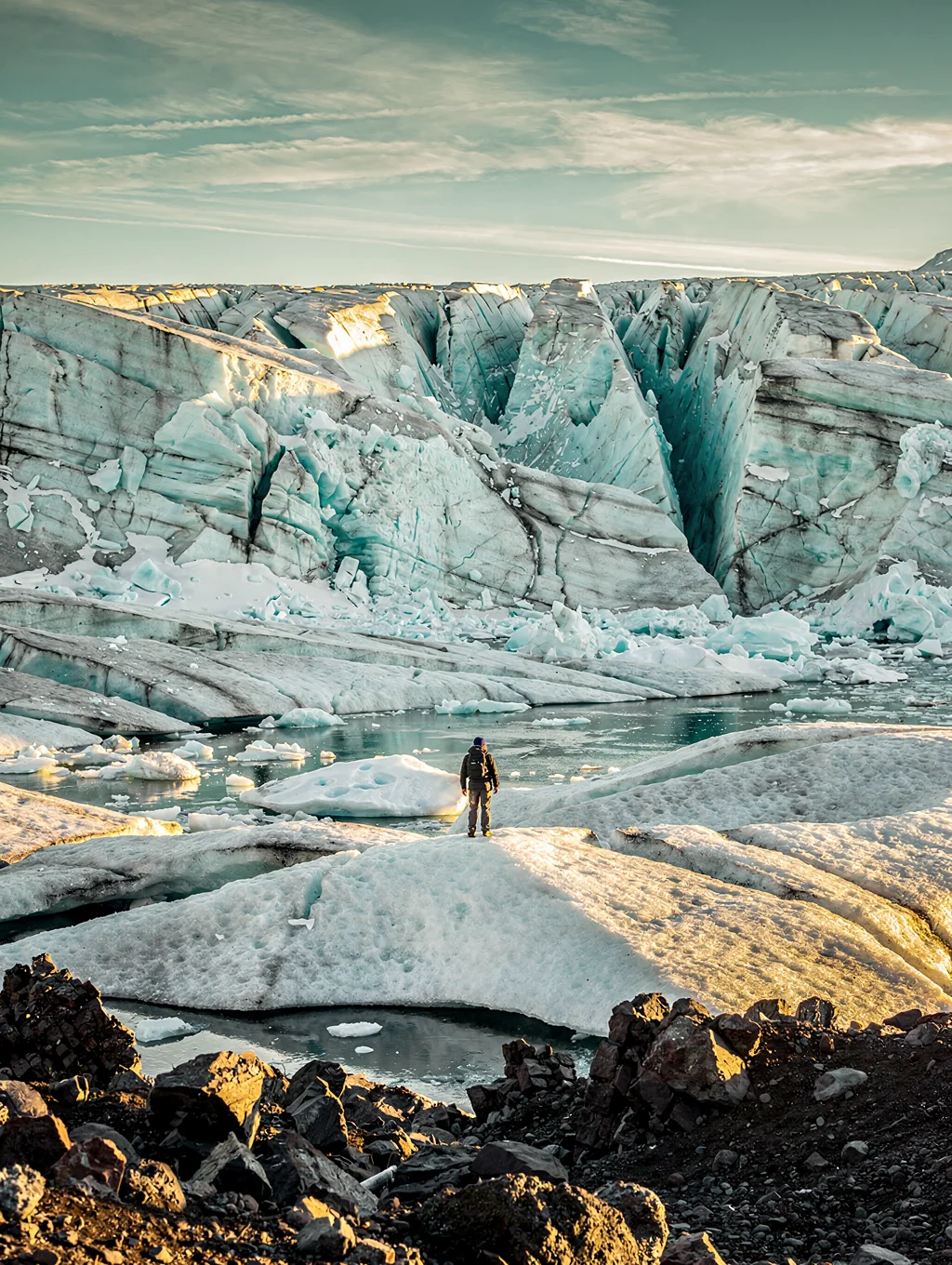 Sunlit arctic glacier face meeting still icy waters under the midnight sun
