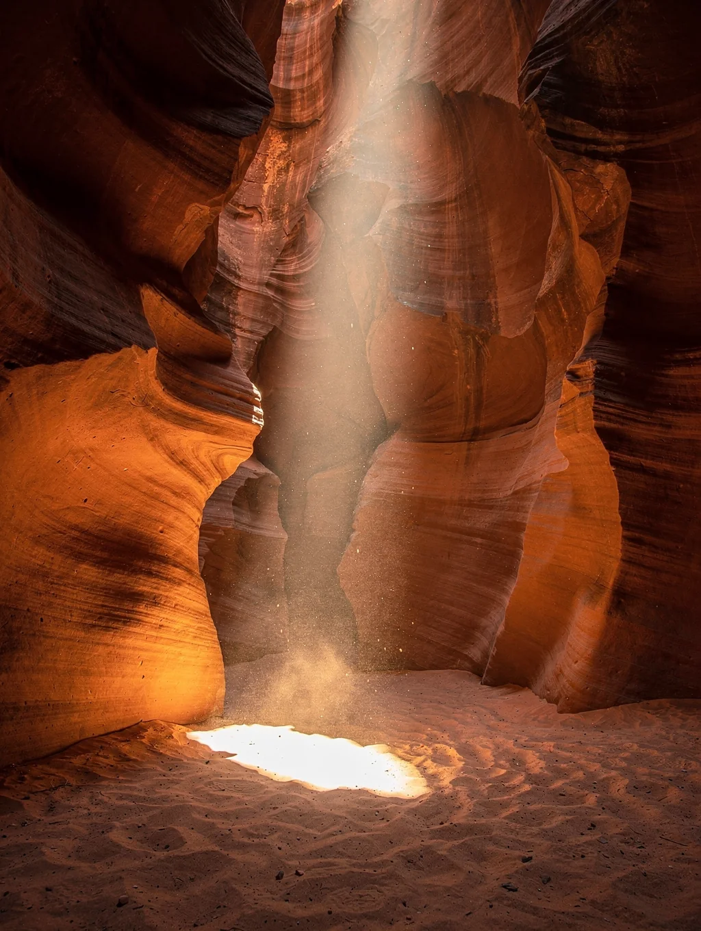 Sunlight beam cascading into the wave-like red sandstone walls of Antelope Canyon