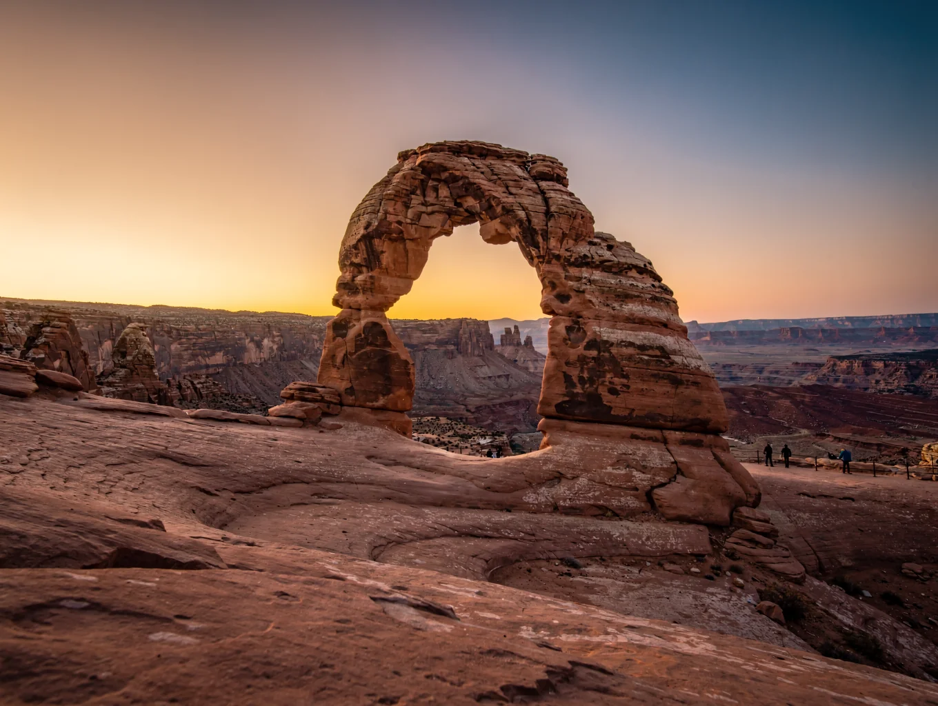 Isolated Delicate Arch perched on red sandstone slickrock at golden hour