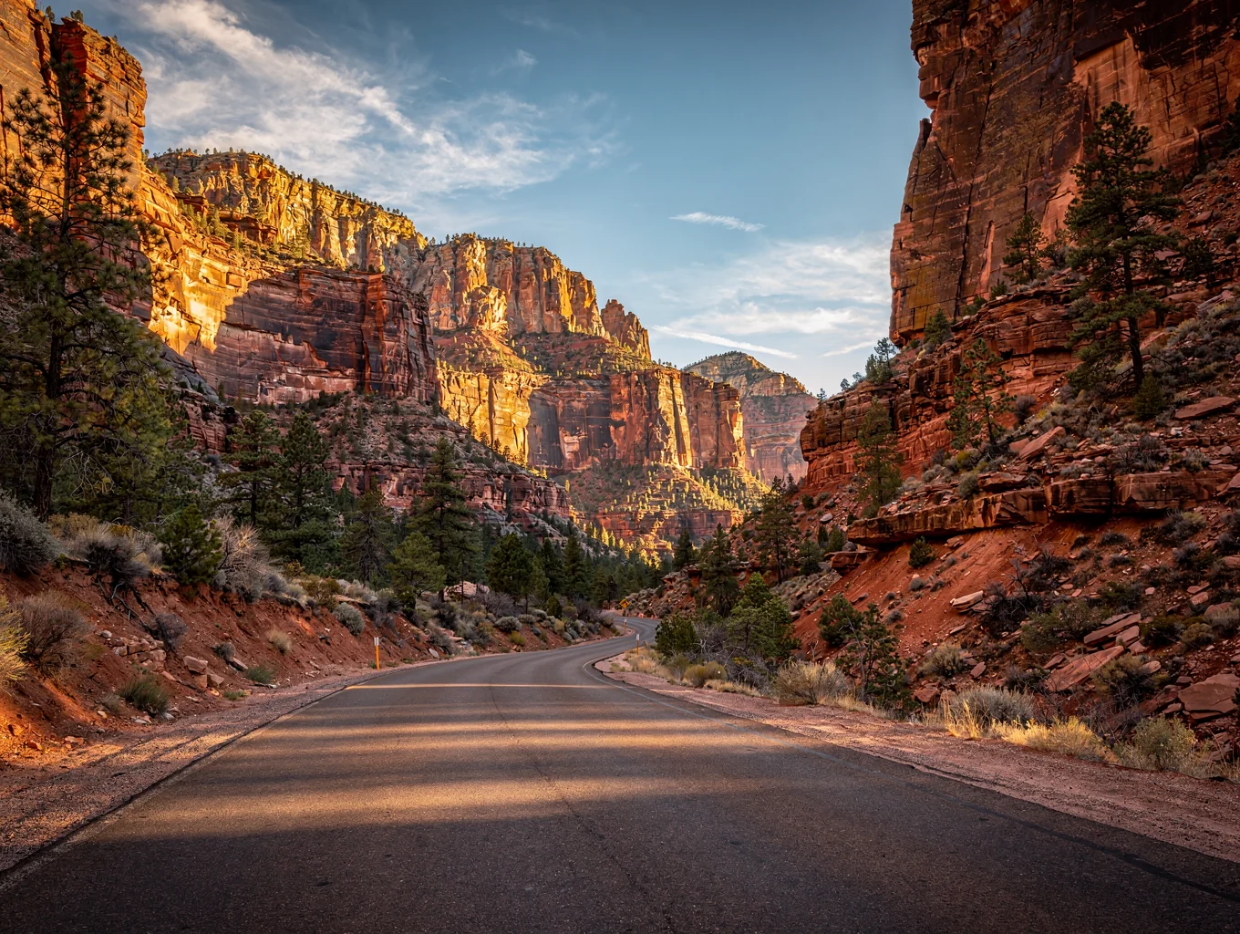 Curved mountain road passing through towering red rock canyon cliffs