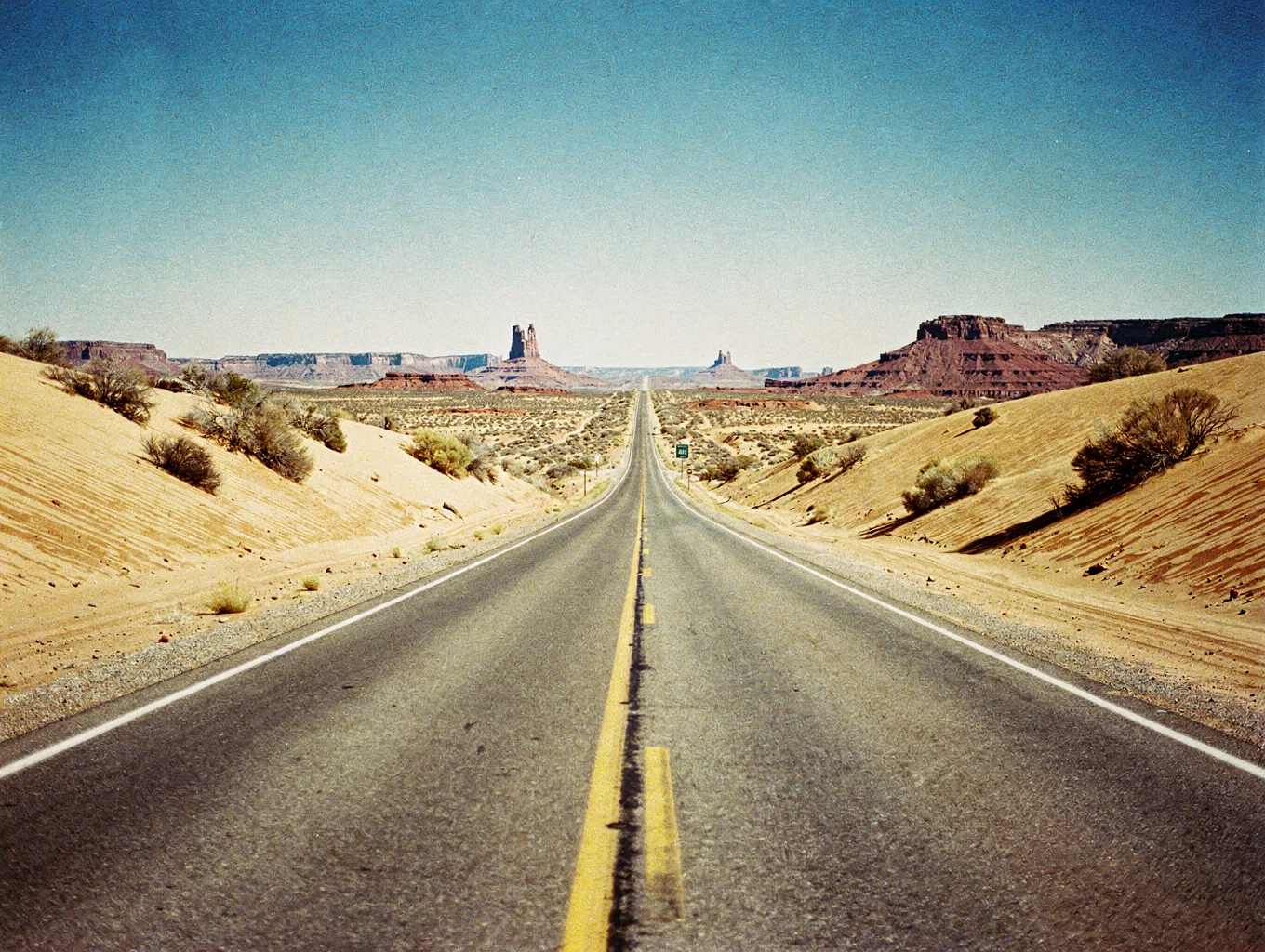 Panoramic highway vista overlooking red rock mesas and open desert landscape